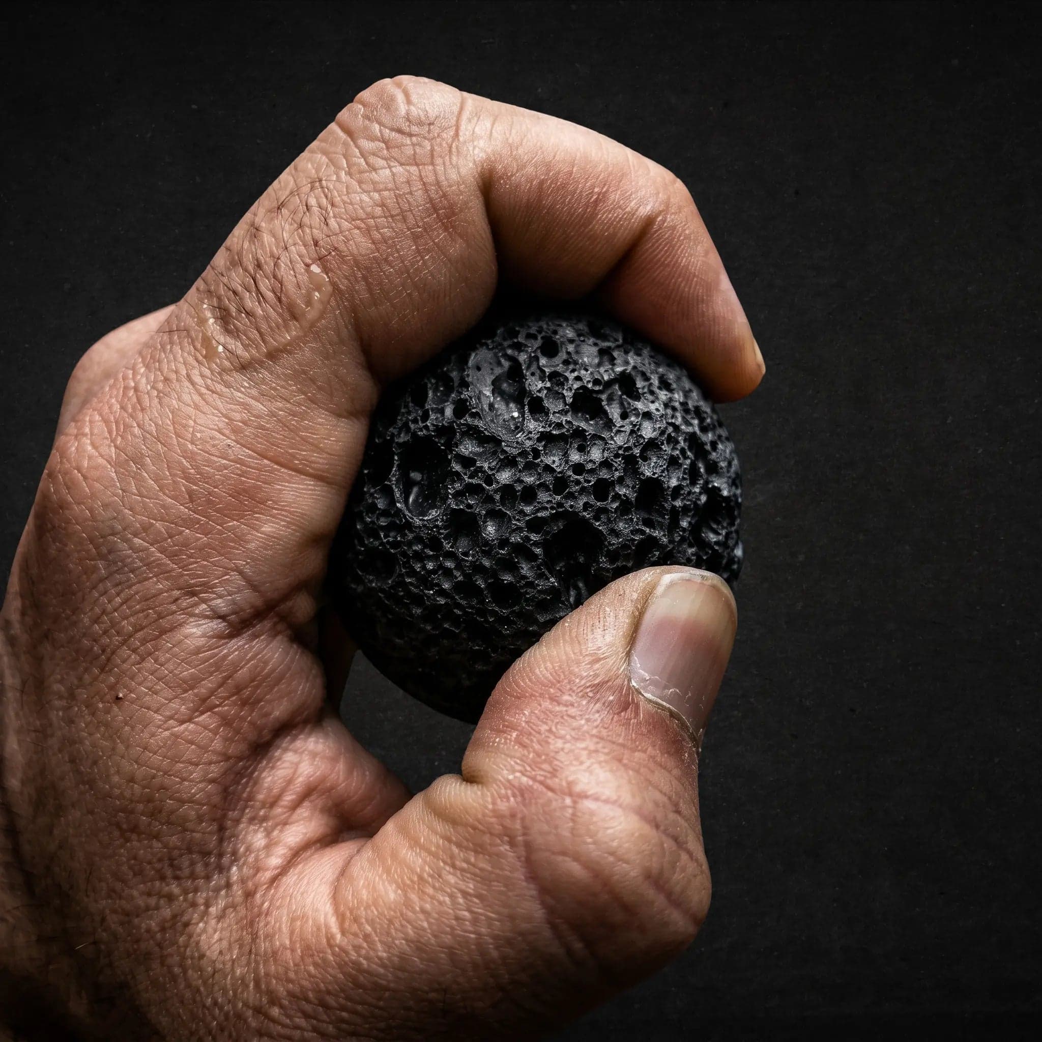 A hand gripping the Moon basalt orb