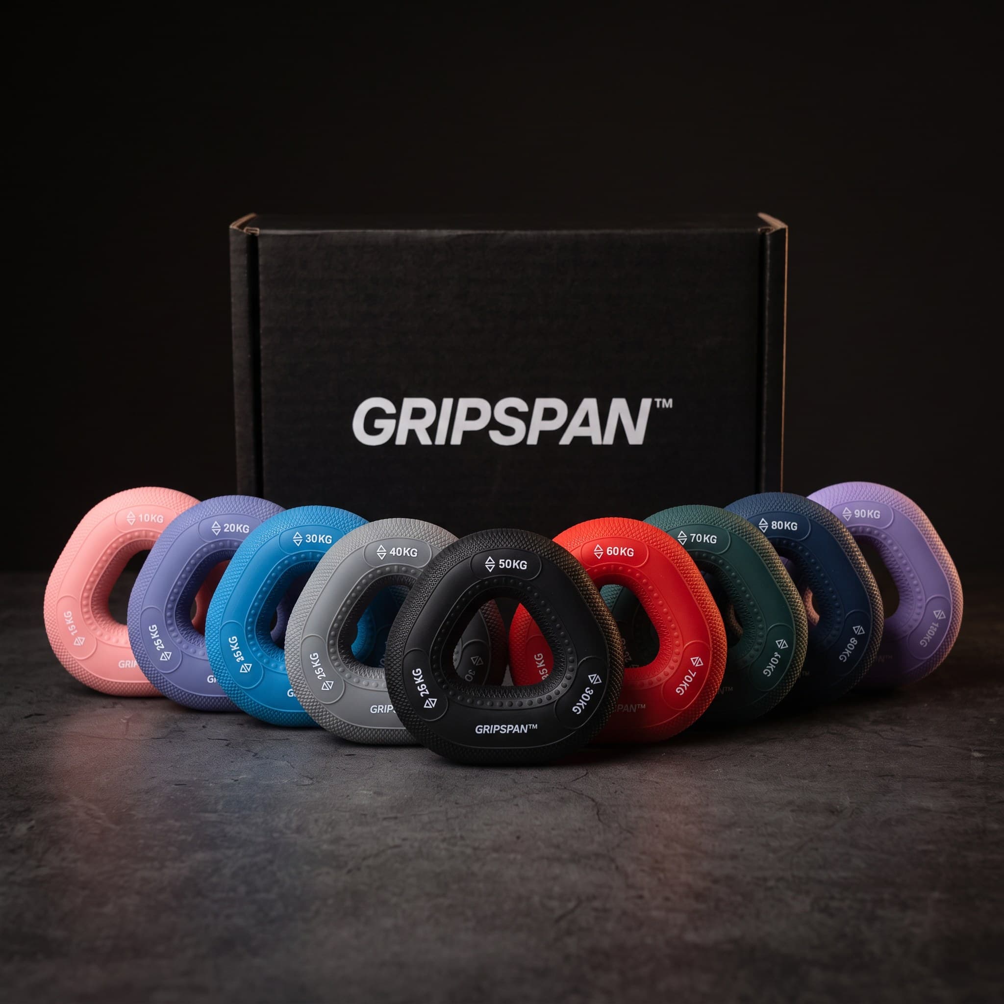 The nine Dad Hands grip rings fanned in front of the Gripspan box, 10 to 90 kg