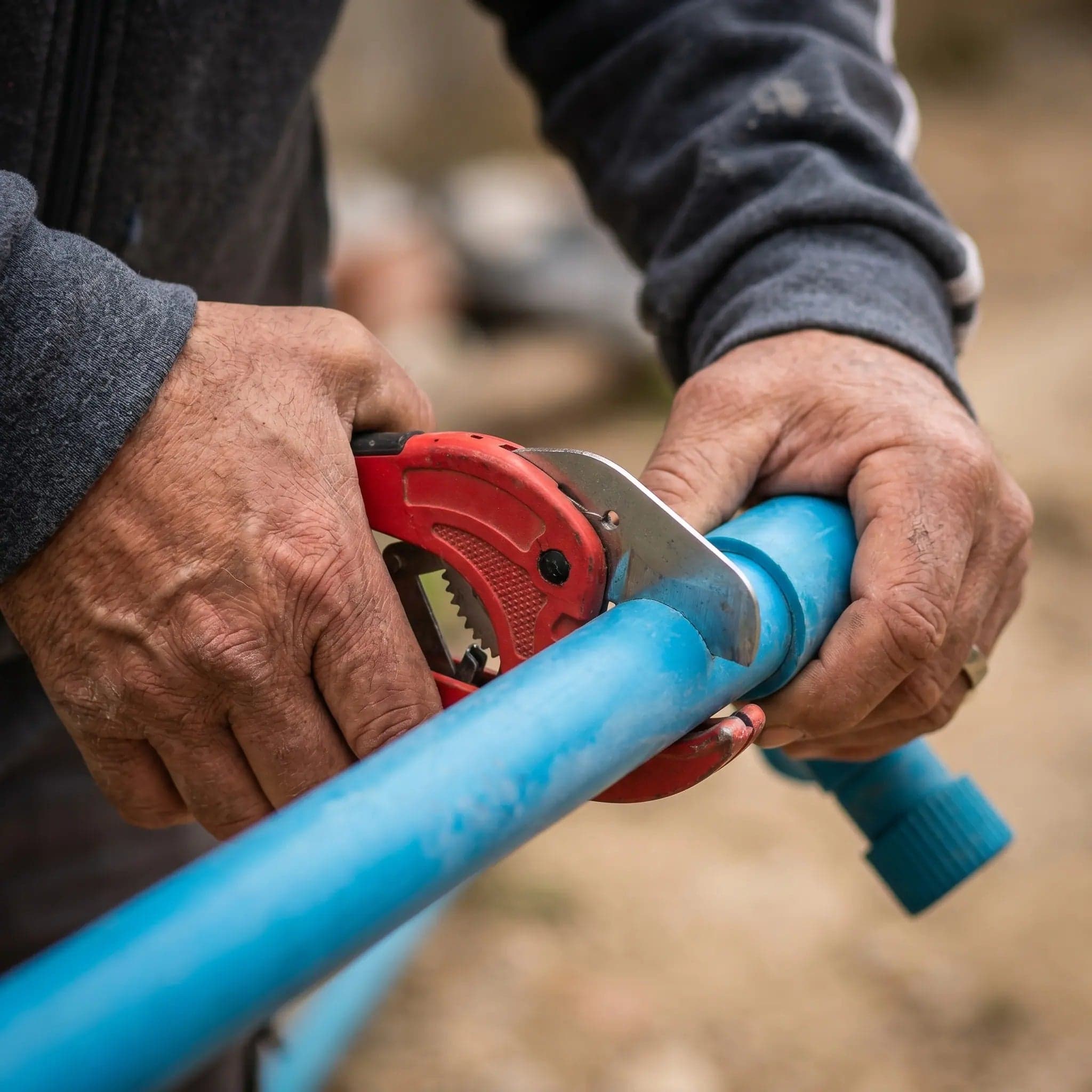 Jesus's hands cutting a pipe on a job site